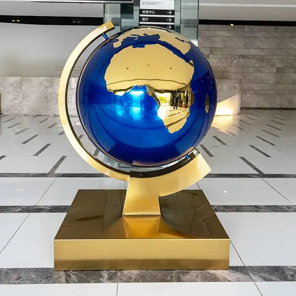 Stainless steel globe sculpture with gold continents and blue oceans on a square base