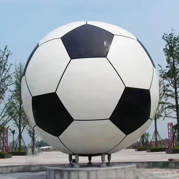 Stainless steel football sculpture painted black and white on a stone pedestal