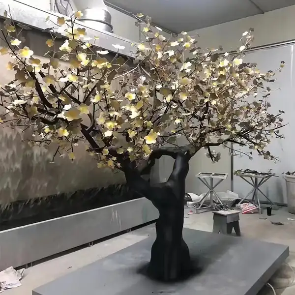Metal blossom tree sculpture with dark trunk and gold leaves in the workshop