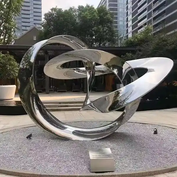 Mirror polished stainless steel interlocking rings sculpture on a plaza plinth