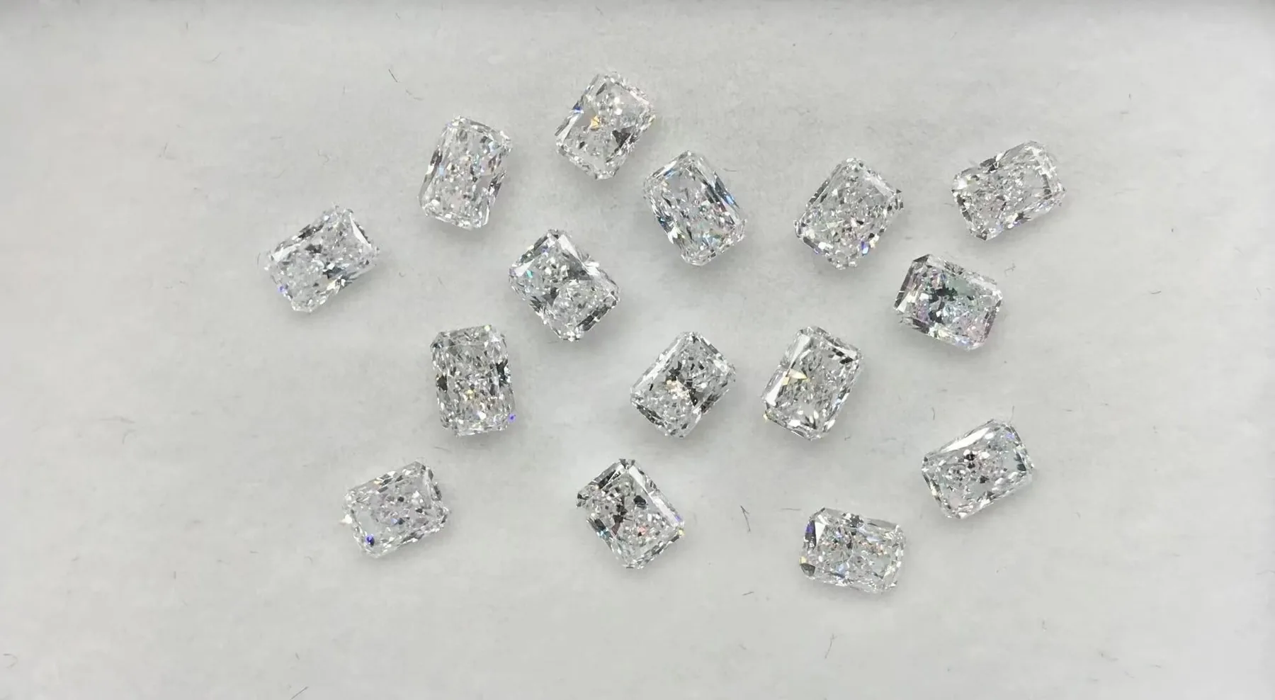Loose matched radiant cut diamonds laid out on a white ground before setting at BH Jewelry