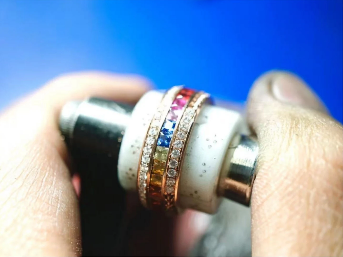 A BH Jewelry craftsperson setting coloured sapphires into a ring at the bench