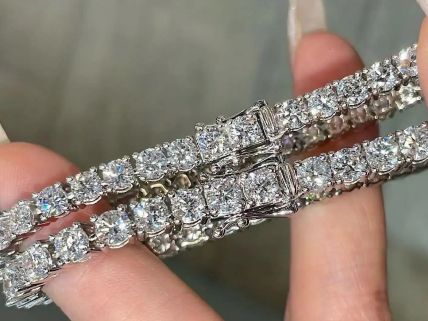 A diamond tennis bracelet held in the hand for inspection at the BH Jewelry bench