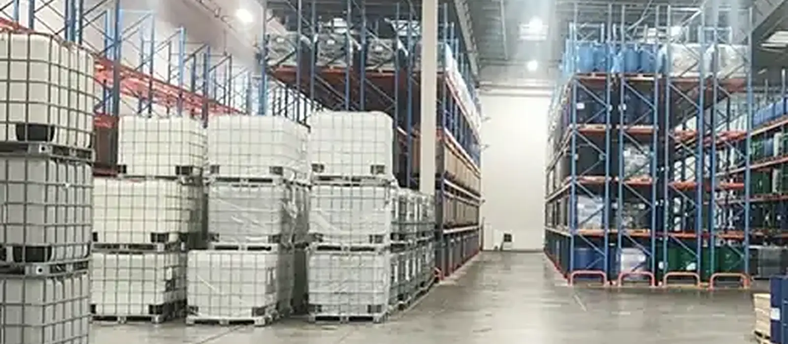 Warehouse aisle stacked with silicone fluid drums prepared for export