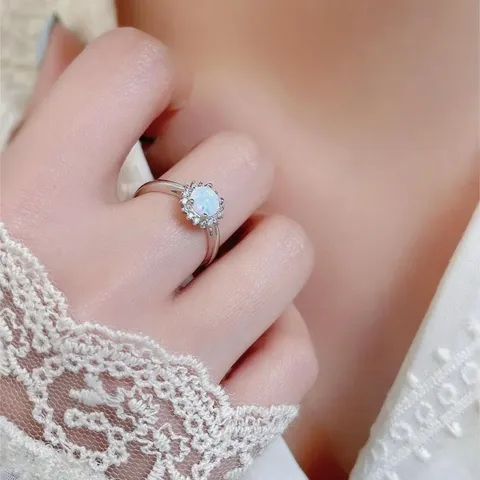 Opal and cubic zirconia ring worn on a hand resting on lace