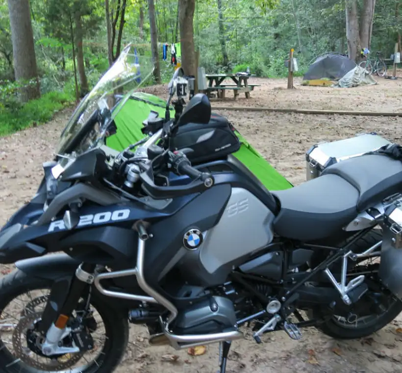 BMW GS adventure motorcycle fitted with Brooks aluminum panniers at a forest campsite