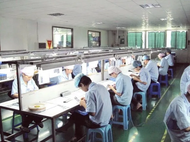 Assembly and winding line. Operators work in caps and coats at fixed benches.