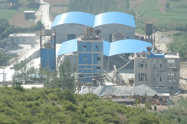 Blue-roofed processing buildings seen from the hillside