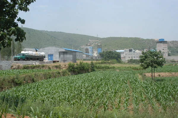 Plant buildings behind green farmland
