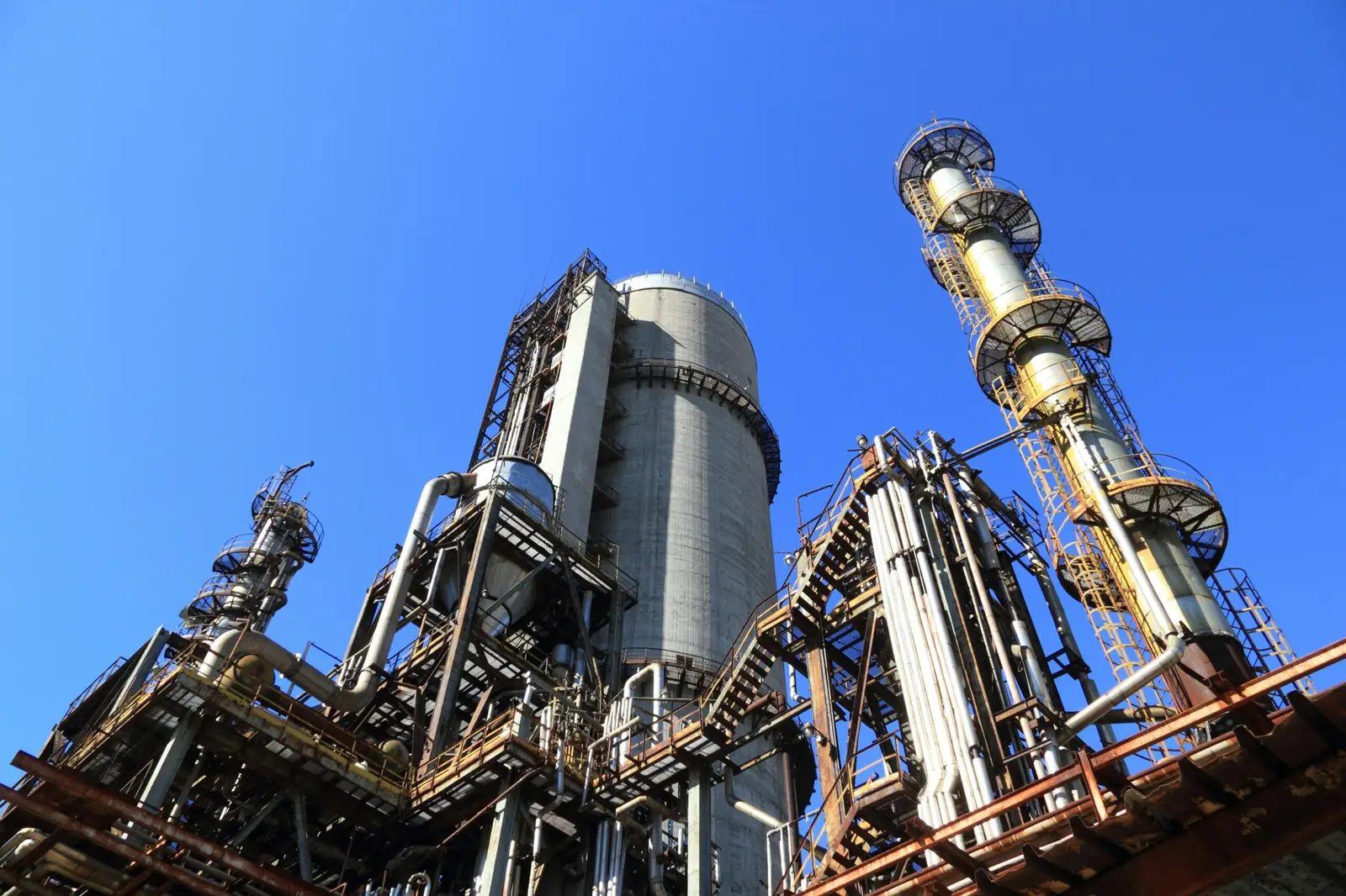 Chemical production plant with reaction columns and storage silos under a clear sky