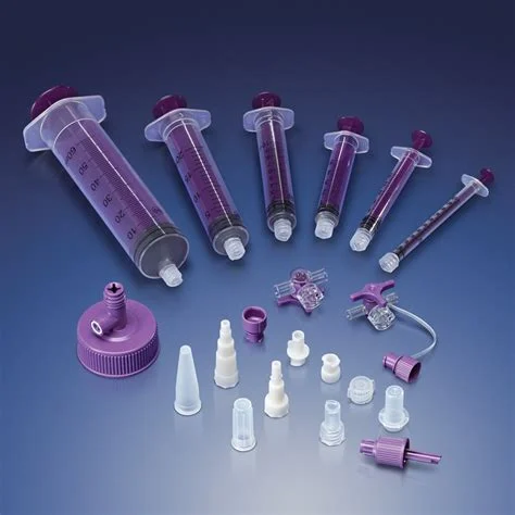 Assorted purple medical enteral syringes, connectors, and caps on a blue background