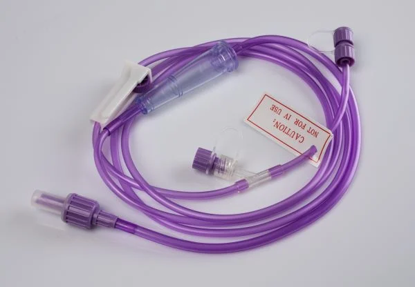 Purple medical tubing set with clamp and caution tag on a plain background