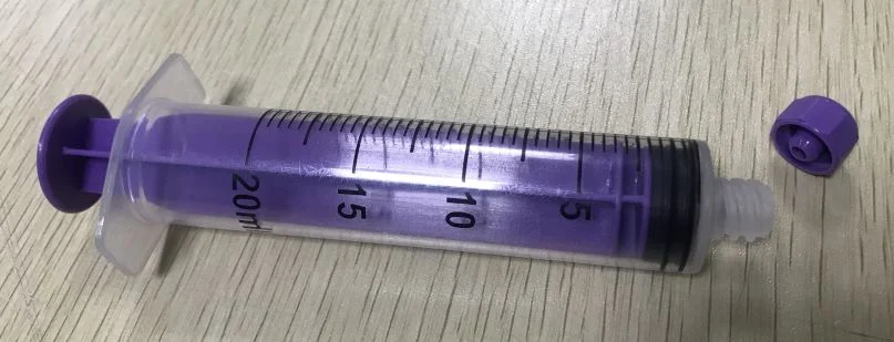 20ml plastic syringe with purple plunger and matching cap on a table