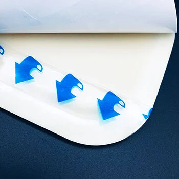 Close-up of peeling adhesive film showing blue arrow peel indicators