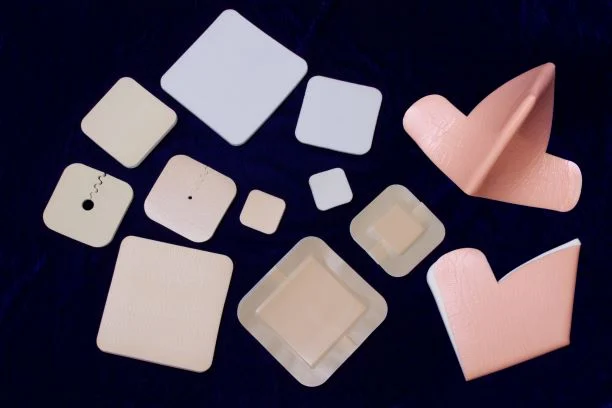 Assorted medical wound dressings and foam patches displayed on a dark surface.
