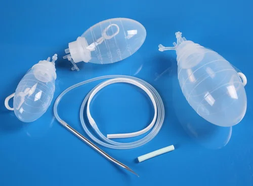 Medical silicone wound drainage bulbs, tubing, and surgical trocar on blue surface