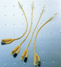Four yellow Foley catheters displayed on a perforated metal surface