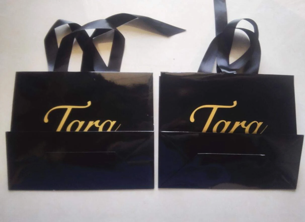 Paper carrier bag with ribbon handle held to show the gusset