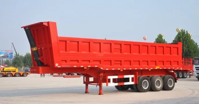 3-axle rear dump trailer parked on a yard, front three-quarter view showing the 10950mm length and 12 tyres
