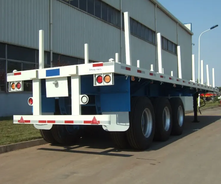 3-axle flatbed semi trailer parked on a yard, front three-quarter view showing 1200R20 tyres and front axle