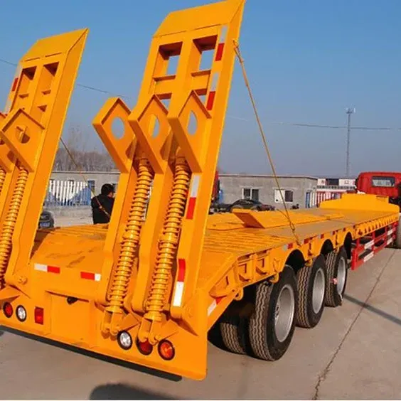 3-axle lowbed semi-trailer parked on a yard, front three-quarter view showing the 13000mm length and 1200R20 tyres