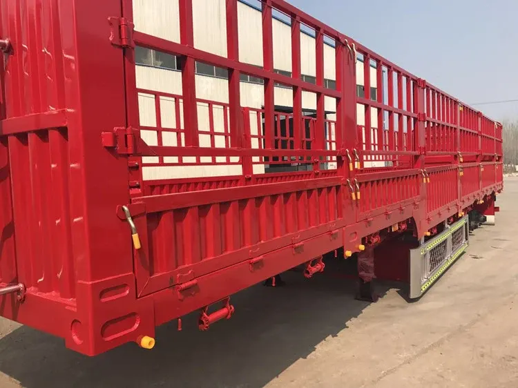 3-axle stake semi trailer parked on a factory yard, front three-quarter view showing side stakes and front axle