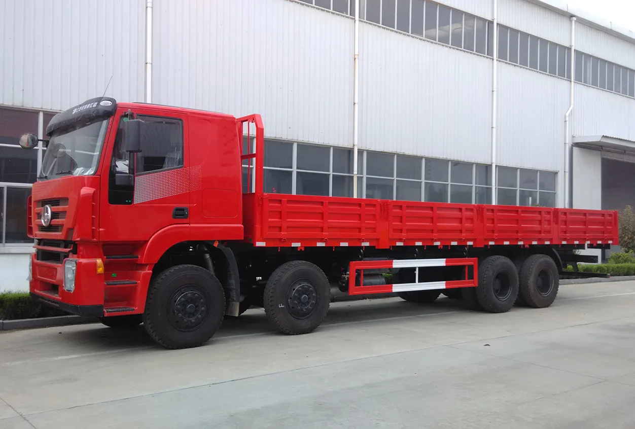 A red flatbed truck parked in front of a white industrial building.