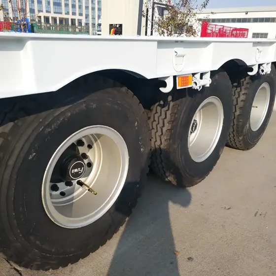 Trailer with hydraulic ladder fully extended and lifting a heavy machine