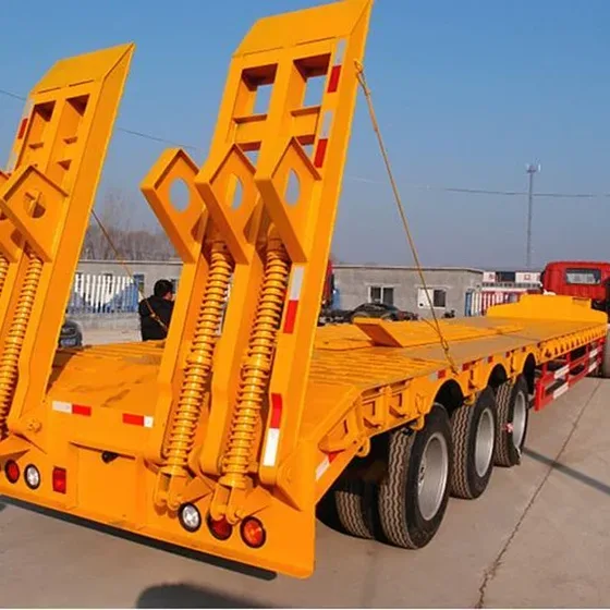 3-axle lowbed semi-trailer parked on a yard, front three-quarter view showing the 13000mm length and 1200R20 tyres