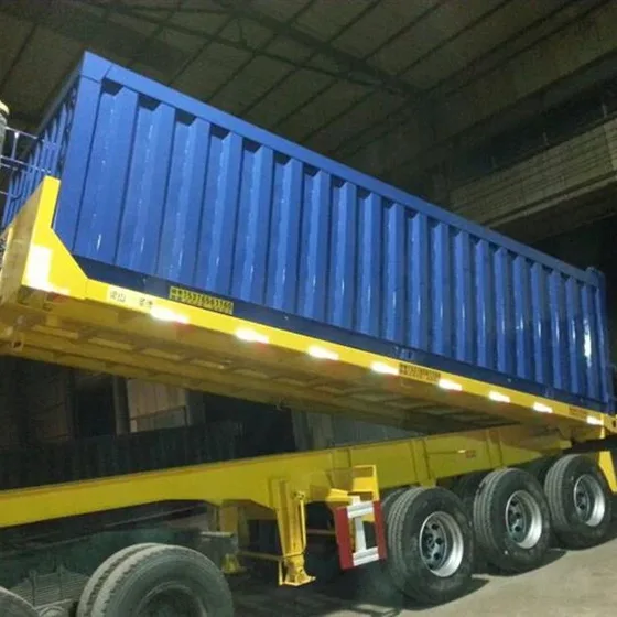 3-axle rear-dump semi trailer in grey paint, front three-quarter view with hydraulic lift arms visible