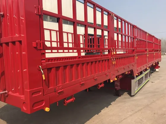 3-axle stake semi trailer parked on a factory yard, front three-quarter view showing side stakes and front axle