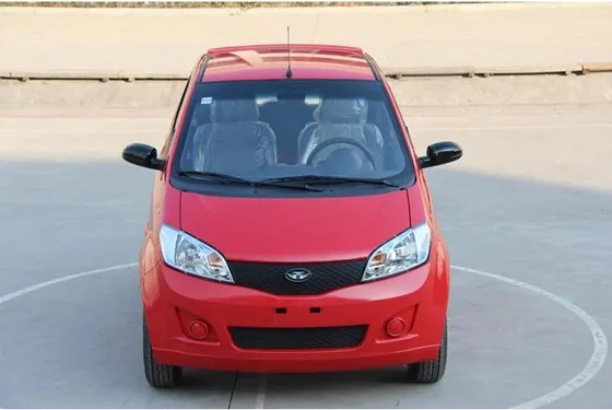 White 3-seater mini electric car with two doors and aluminum wheels parked on a concrete lot