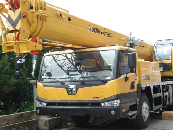 White QY25K-II mobile hydraulic truck crane on a yard, front three-quarter view with boom extended