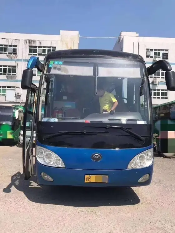 Used 10m electric city bus parked on a yard, front three-quarter view with air-conditioner unit visible