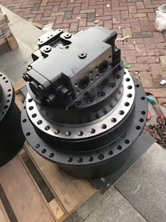 Close-up of the final drive reducer gearbox 20Y-27-00500 mounted on an excavator frame, showing the housing and mounting flanges