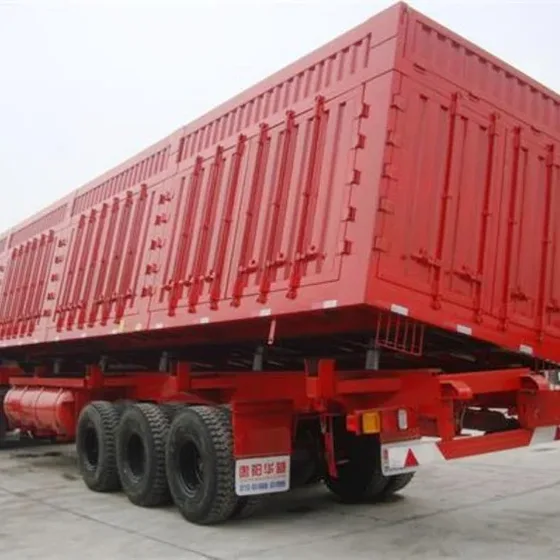 Side dump semi trailer in white, parked on a yard with side gate open