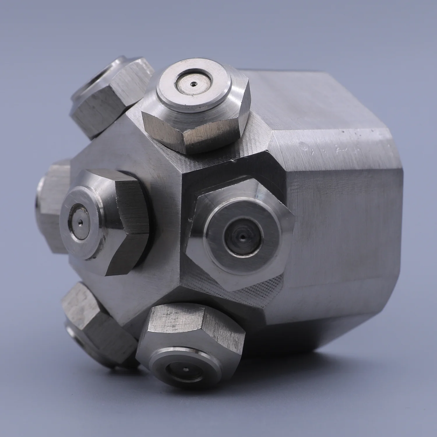 Stainless steel multi-port manifold block with hexagonal fittings and central orifices