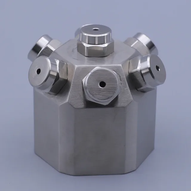 Stainless steel hexagonal manifold block with multiple capped ports on a gray background