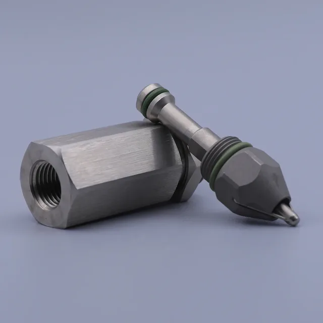 A threaded metal hydraulic cartridge valve body and a disassembled spool with green o-rings resting on a blue-grey backg