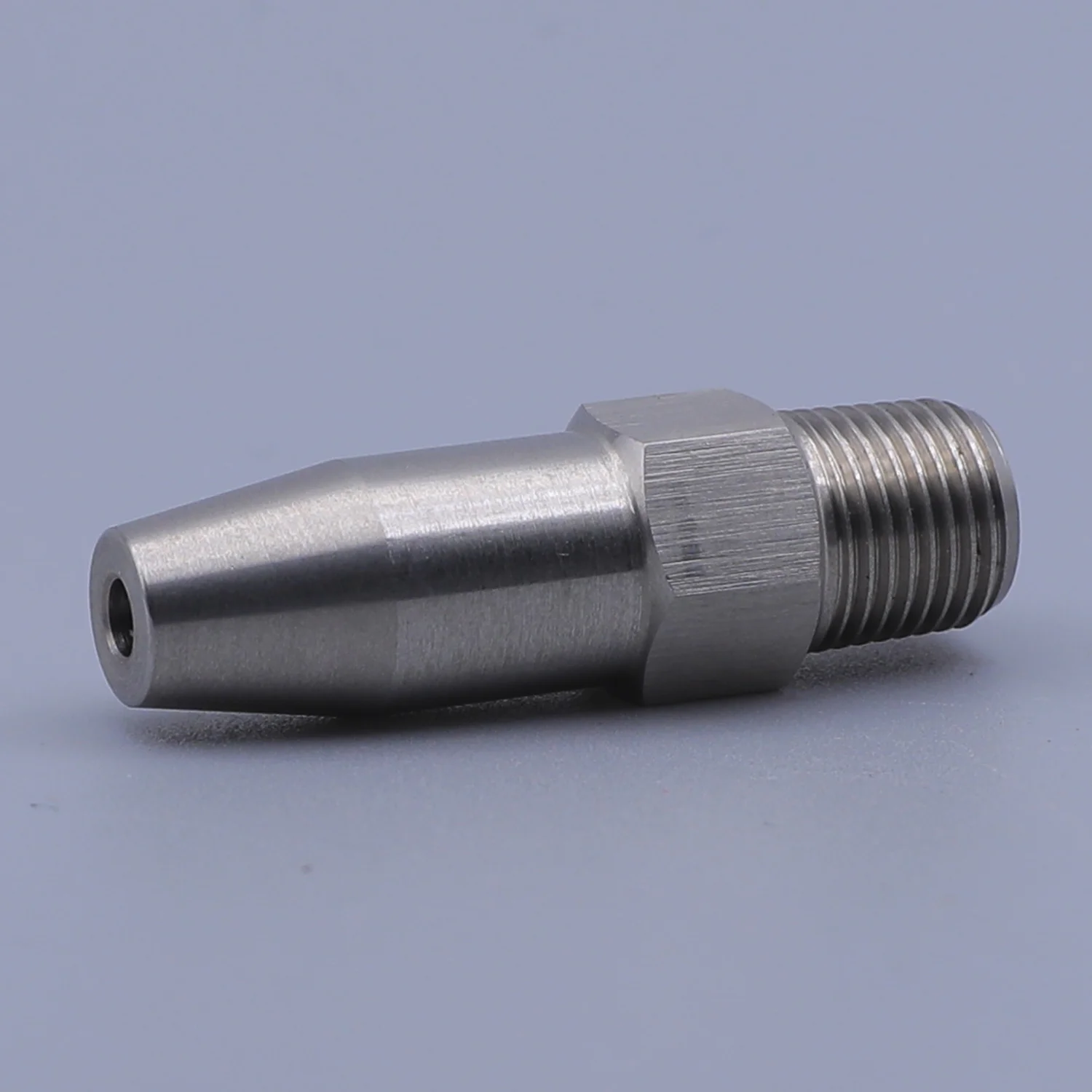 Stainless steel nozzle with external threads and a hex body on a plain background