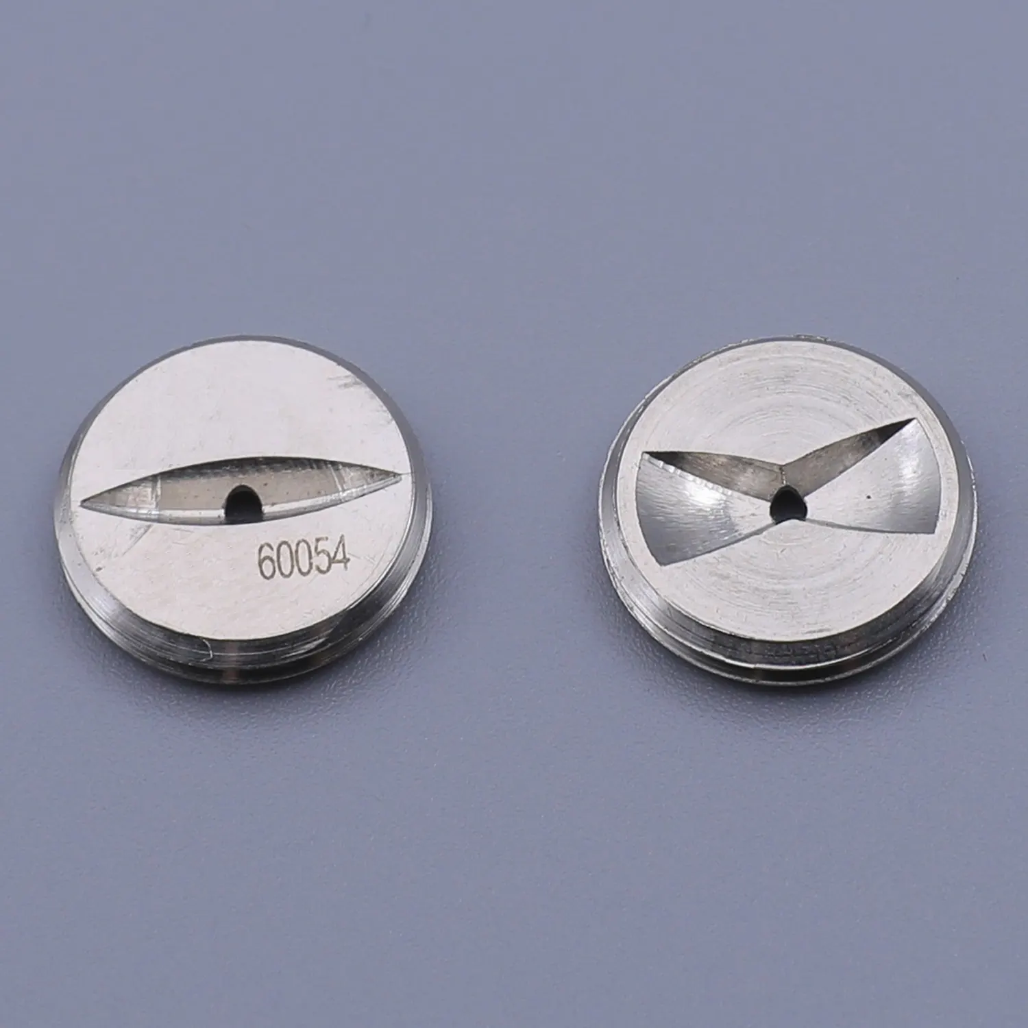Two round metal extrusion dies, one with a single slot and one with a three-point star shape, on a grey background