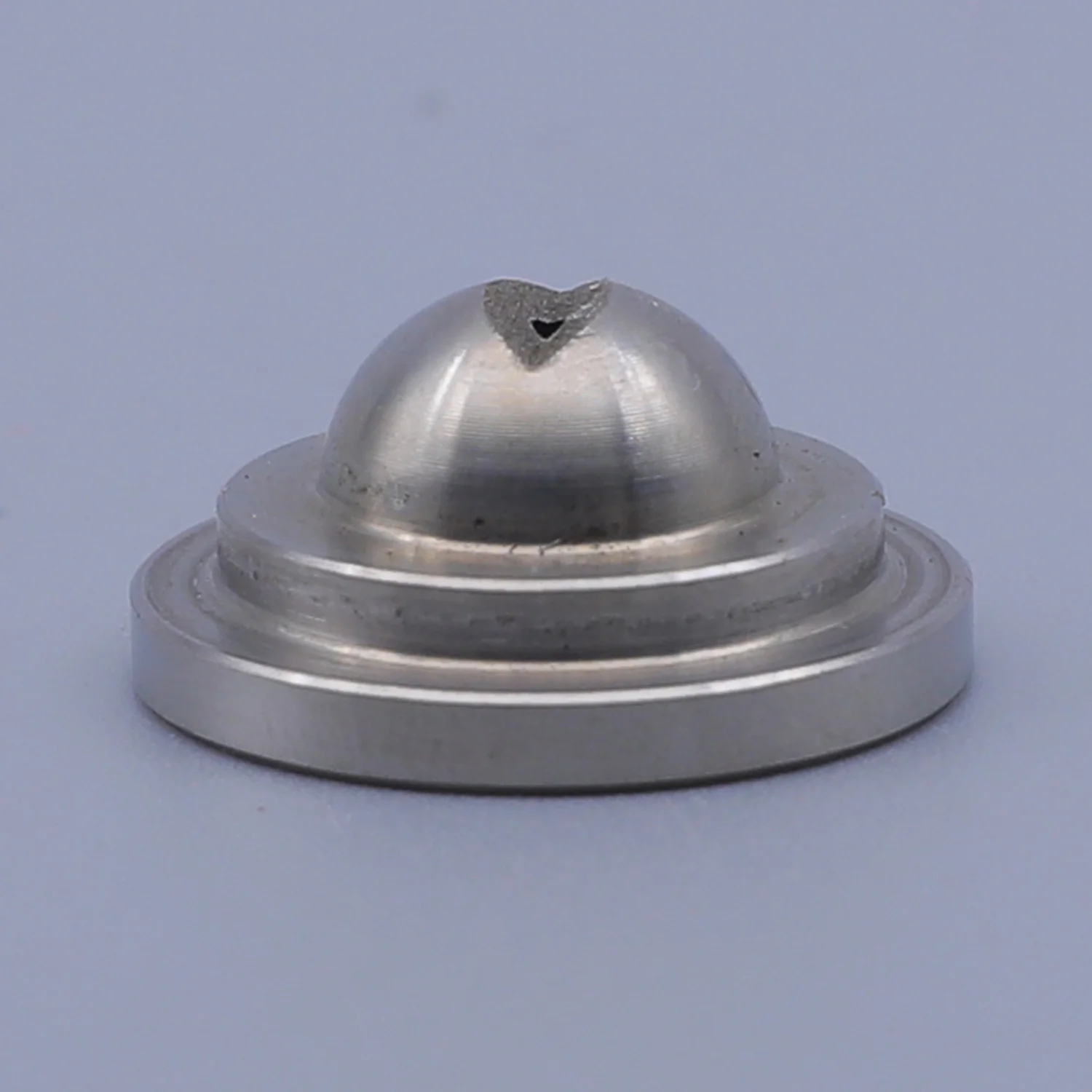 Metal component with a domed top and circular base, featuring a small V-shaped notch at the apex