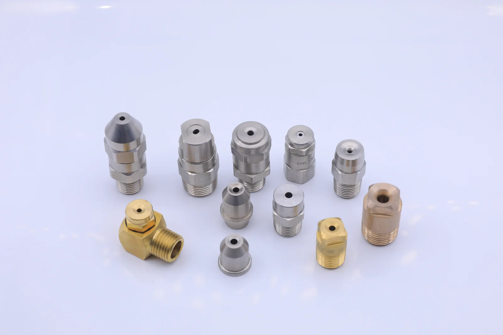 Assortment of brass and stainless steel industrial spray nozzles on a white background