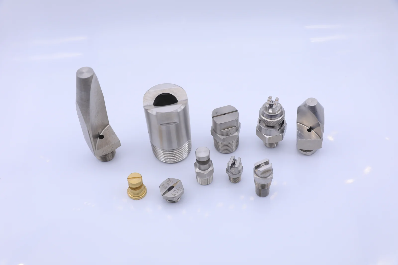 Assortment of stainless steel and brass industrial spray nozzles on a white background