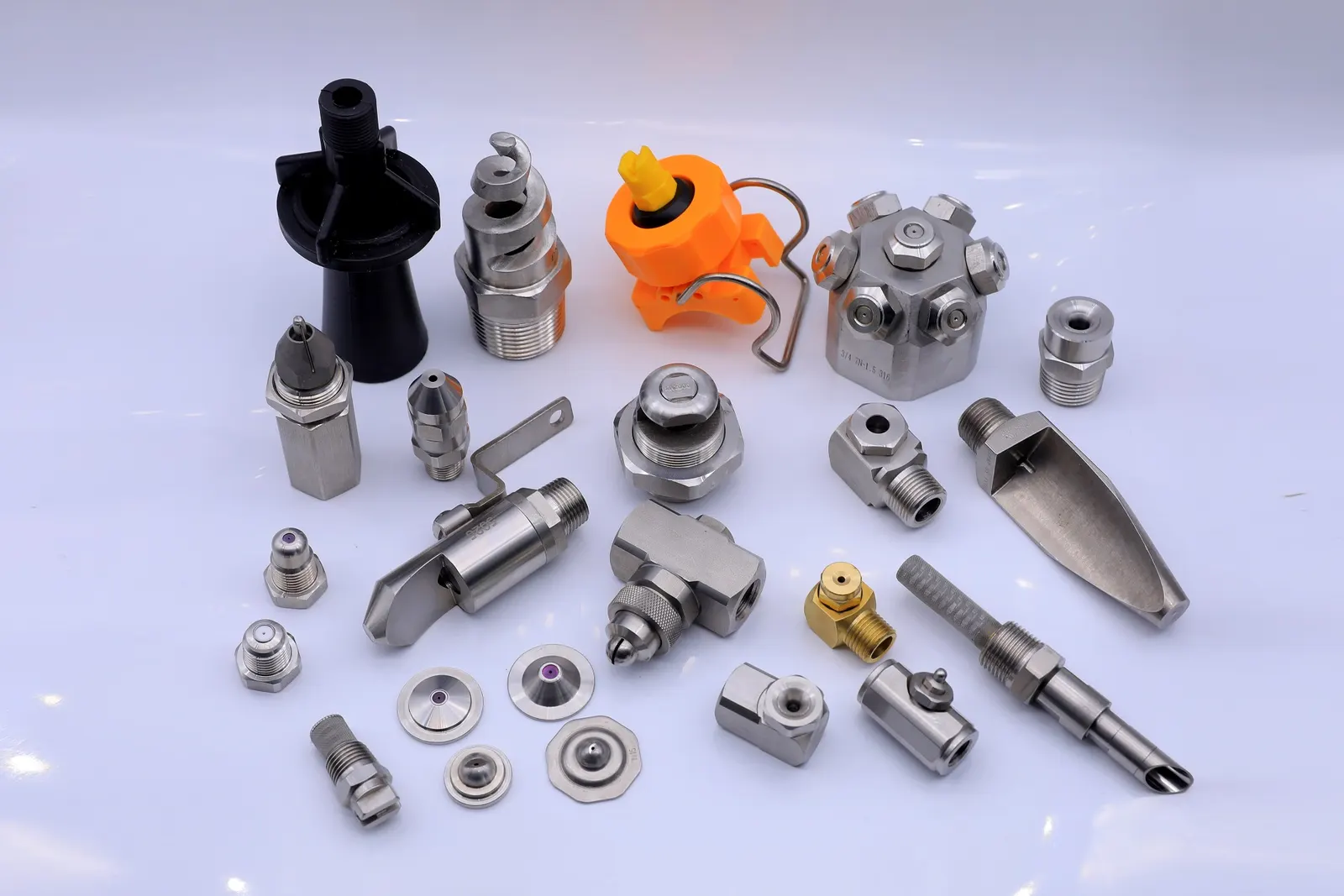 A collection of various industrial spray nozzles and fittings arranged on a white background