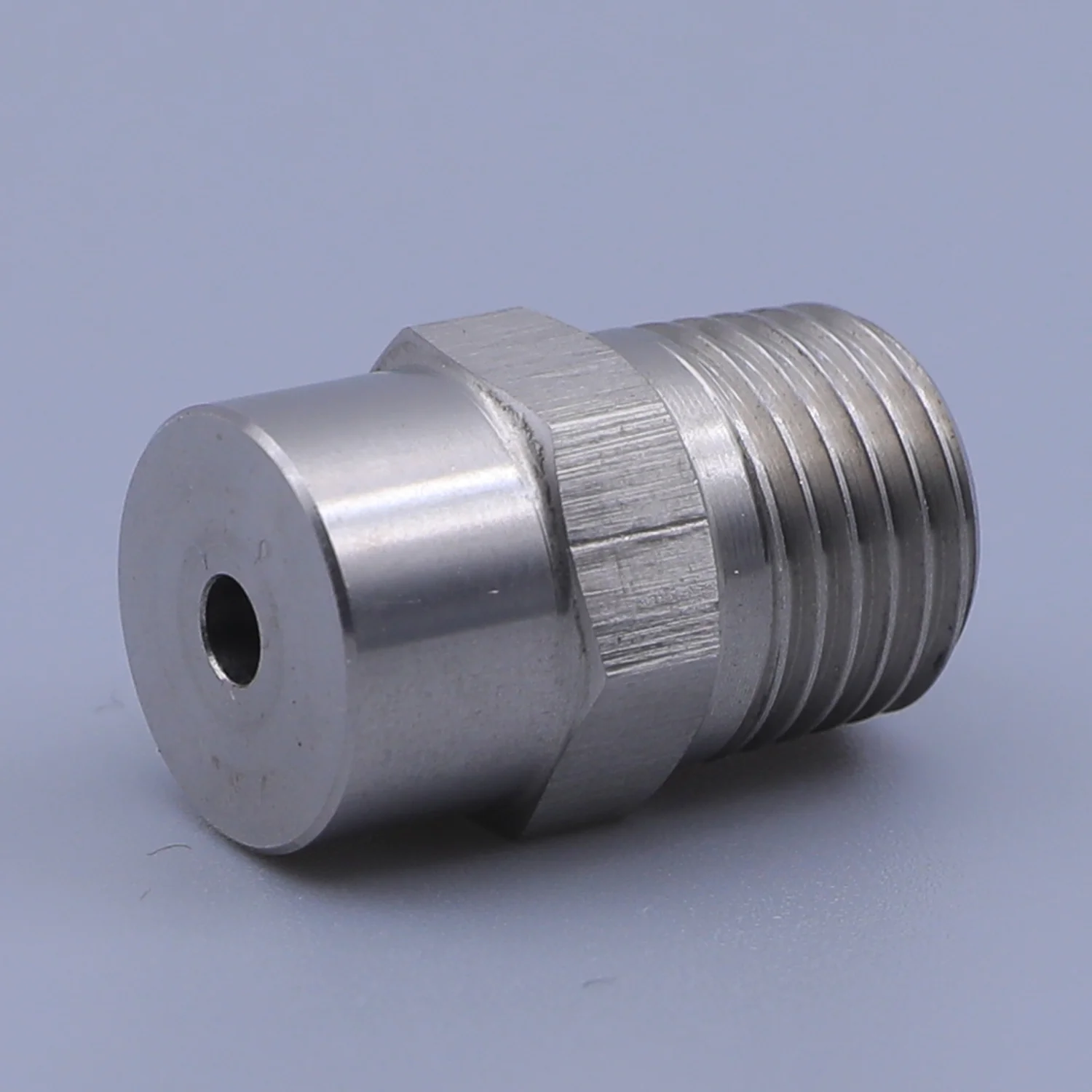 Stainless steel threaded fitting with hex body and small central bore on a plain background