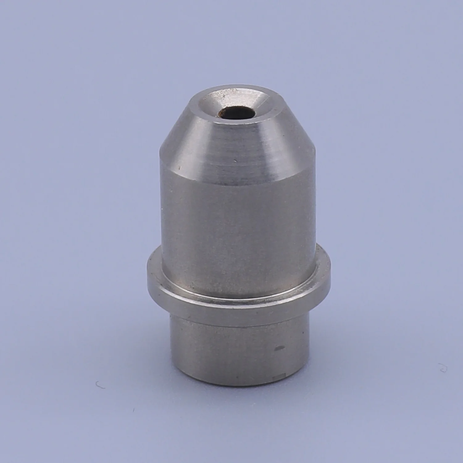 A machined metal component with a central hole and a stepped base