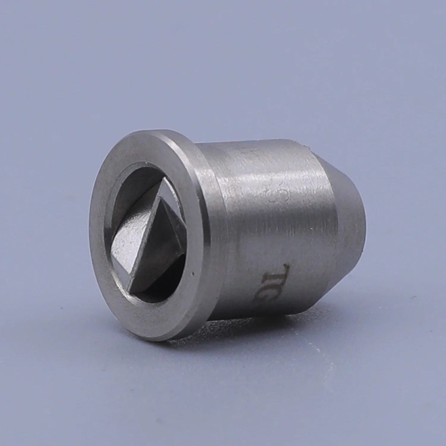 A close-up of a cylindrical metal component with a diamond-shaped aperture on a plain background