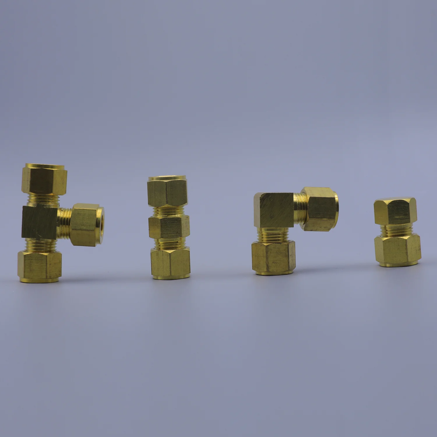 Four brass compression fittings arranged in a row on a gray background