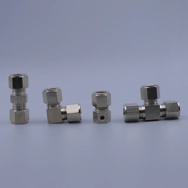 Four stainless steel hydraulic fittings including straight, elbow, tee, and bulkhead connectors on a gray background